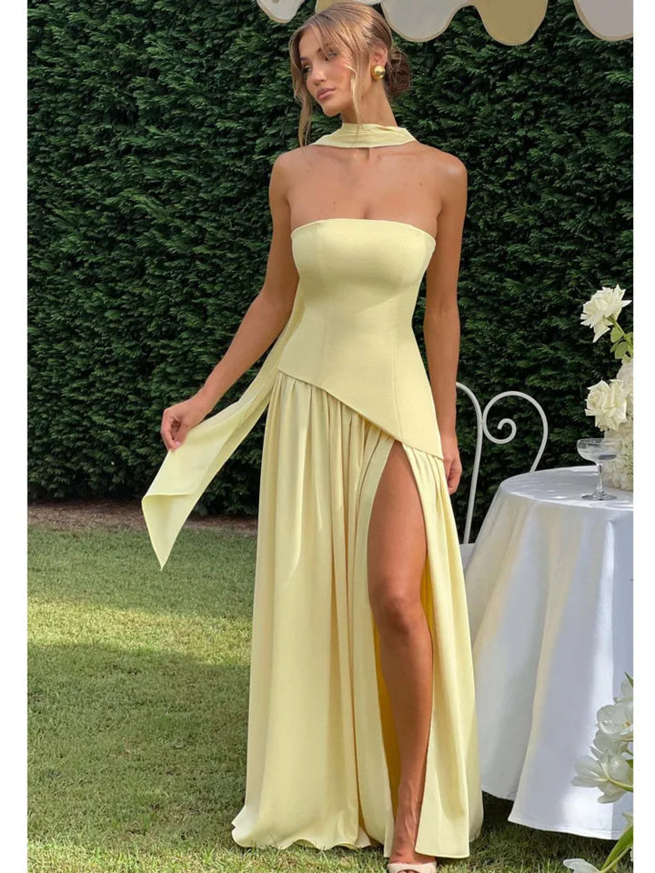 Woman wearing a light yellow strapless dress with a slit, standing outdoors.