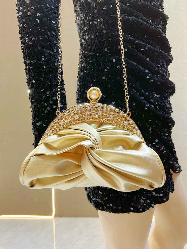 Gold clutch purse with a textured surface on a mannequin wearing black sequin dress.