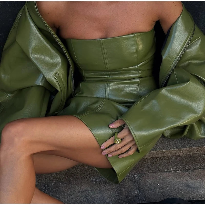Person wearing a green leather outfit sitting on a stone surface.