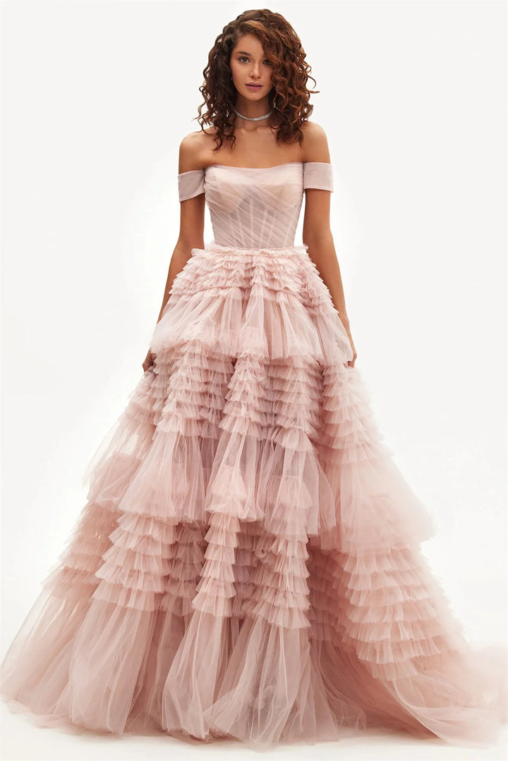 A model wearing an off-the-shoulder pink maxi dress with a layered tulle ruffle and organza fabric.