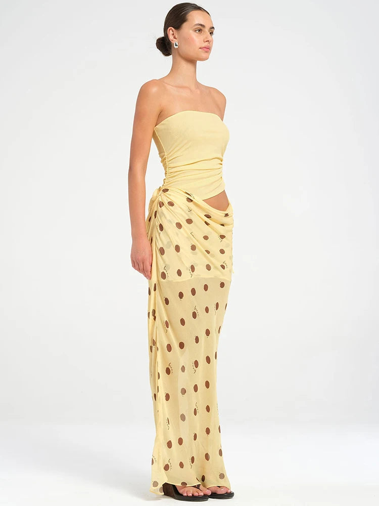Woman wearing a yellow strapless top and polka dot skirt on a white background