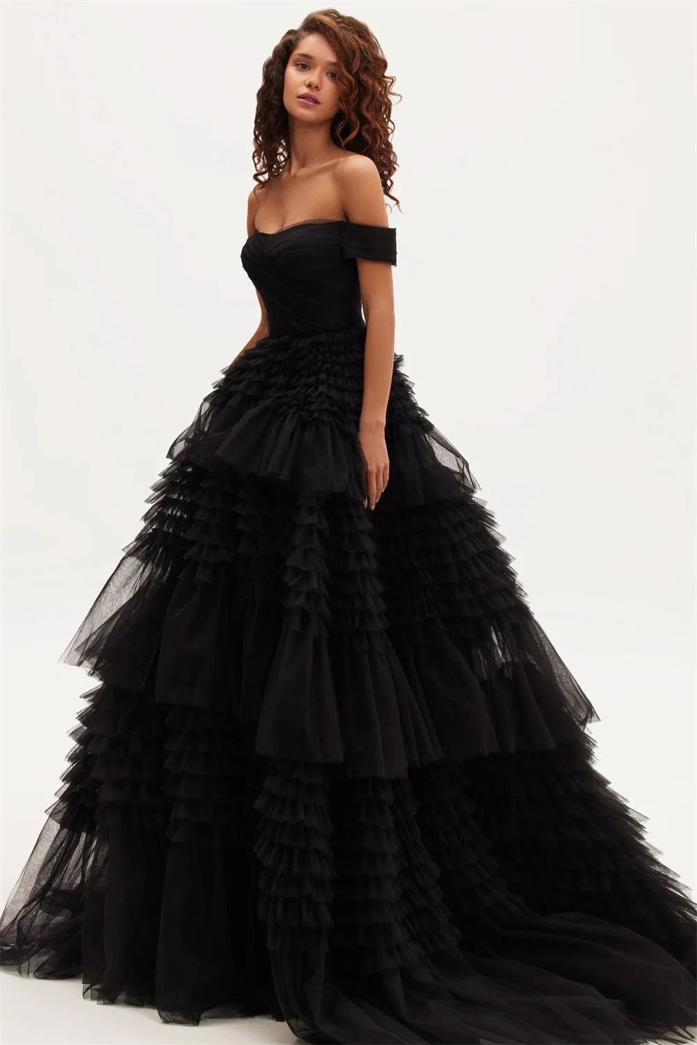 A model wearing an off-the-shoulder black maxi dress with a layered tulle ruffle and organza fabric.