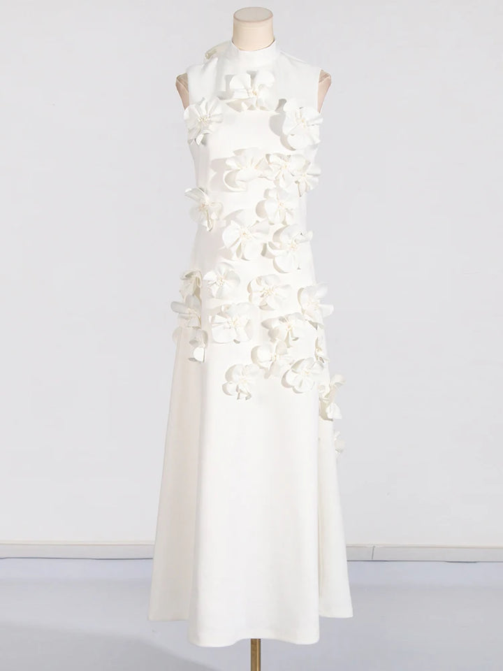 A model wearing a sleeveless, high-waisted, maxi dress with patchwork appliques and a stand collar.