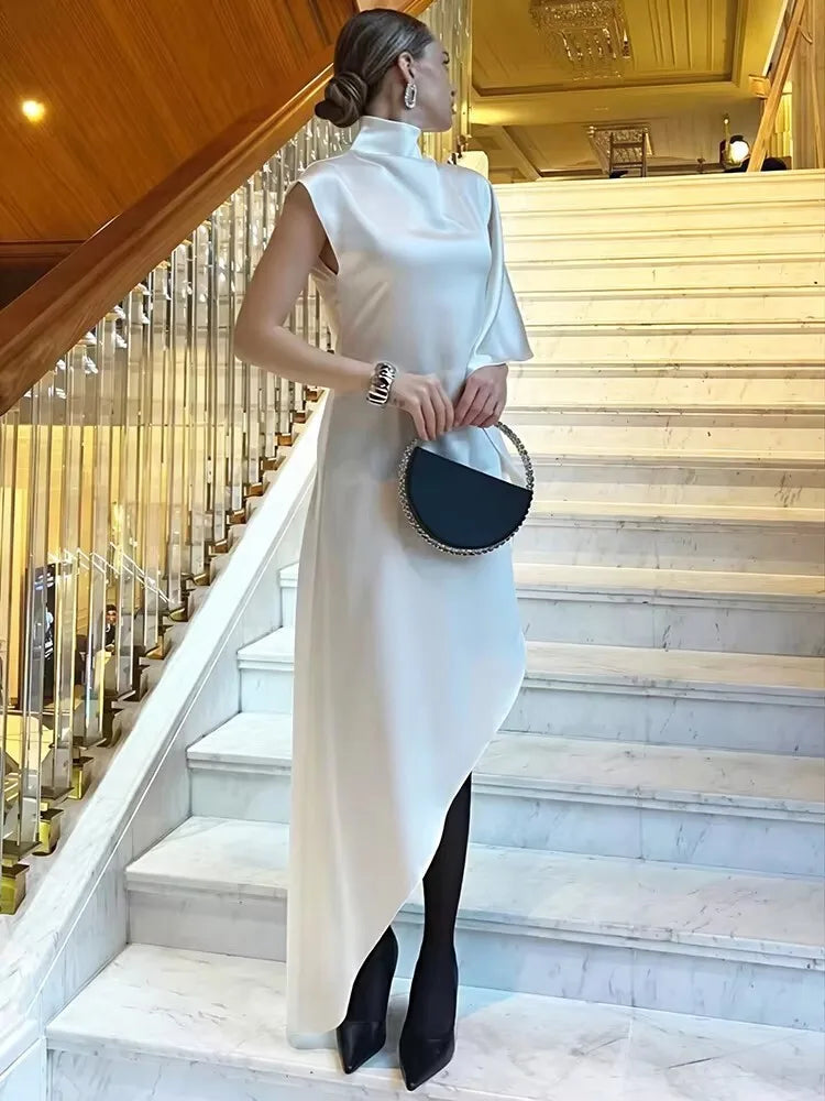 Model wearing the elegant Kiersten Maxi Dress on a staircase, showcasing its asymmetrical hem and chic turtleneck.