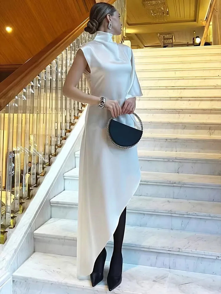 Model wearing the elegant Kiersten Maxi Dress on a staircase, showcasing its asymmetrical hem and chic turtleneck.