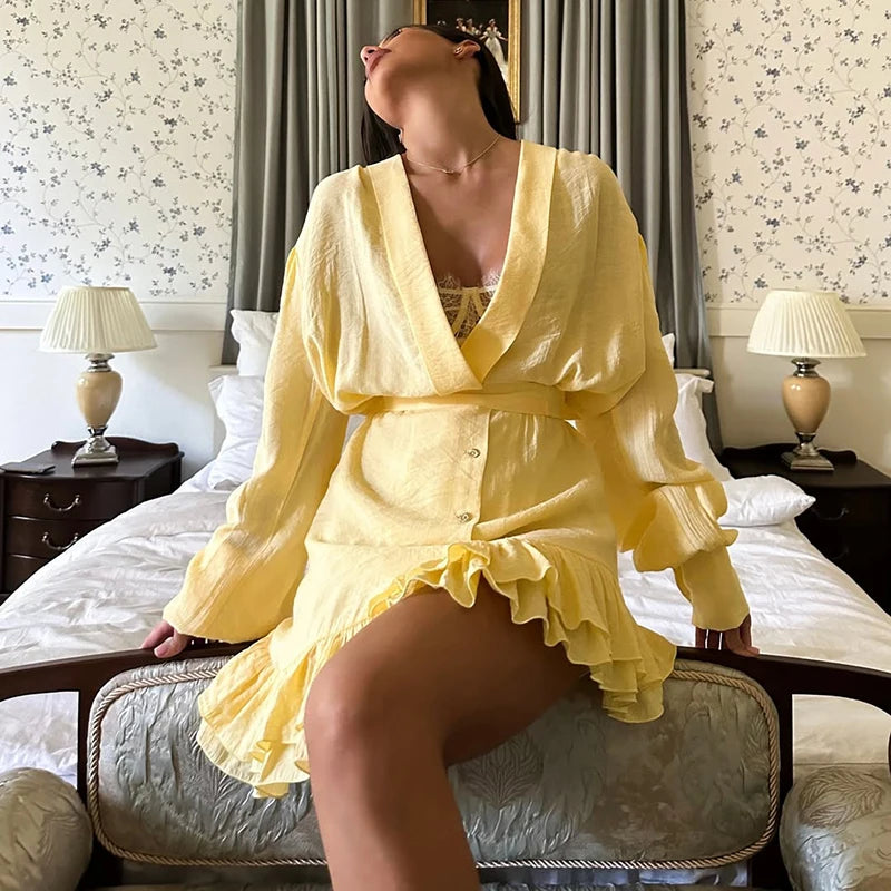 Woman in a yellow outfit sitting on a bed in a bedroom.