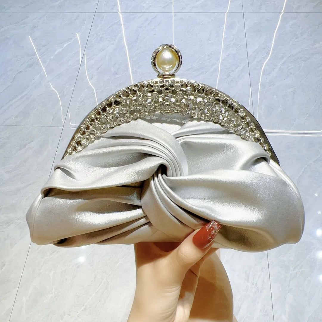 Silver clutch with decorative frame held by a hand against a light background