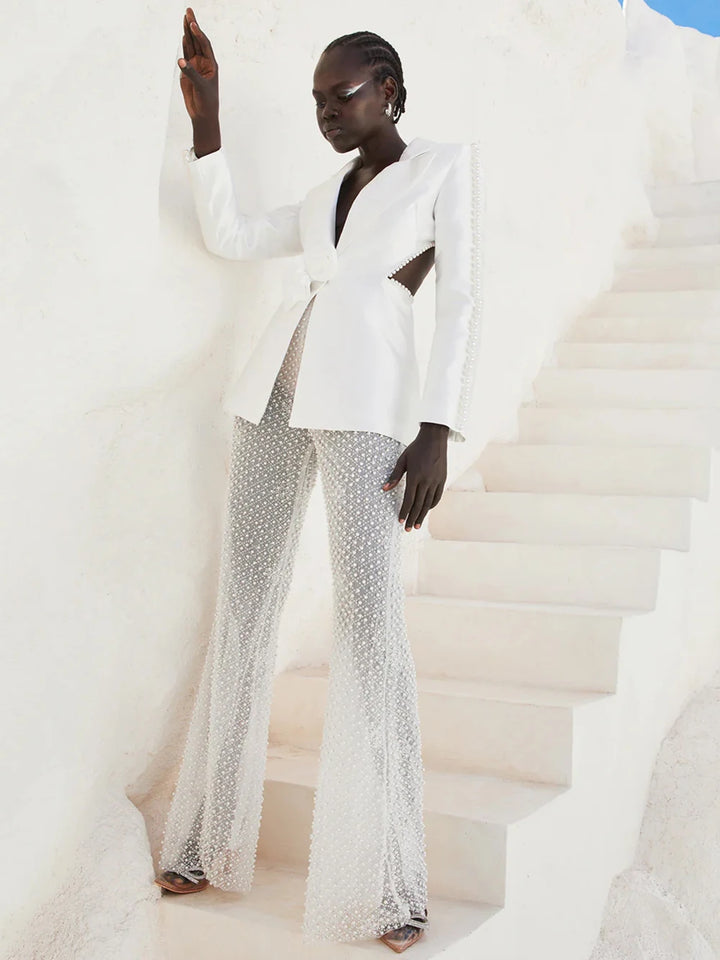 Woman in a stylish white outfit with embellishments standing on a city street.