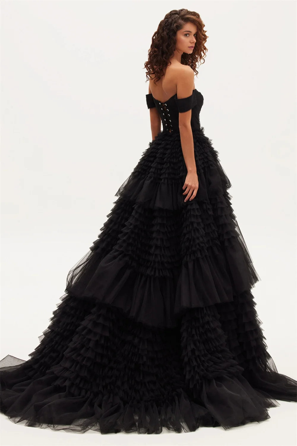 A model wearing an off-the-shoulder black maxi dress with a layered tulle ruffle and organza fabric.