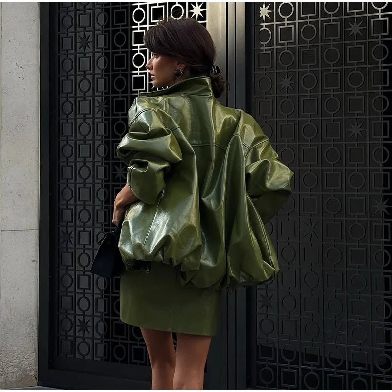 Person wearing a green leather jacket standing against a decorative black door.