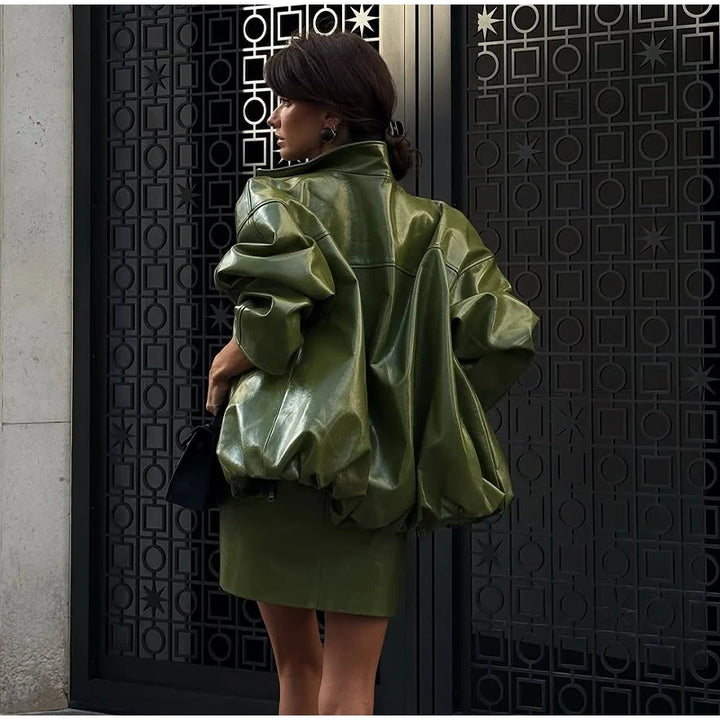 Person wearing a green leather jacket standing against a decorative black door.