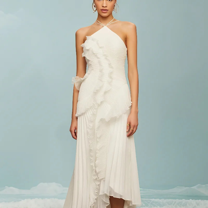 Woman wearing a white halter neck dress with ruffled details against a light blue background.