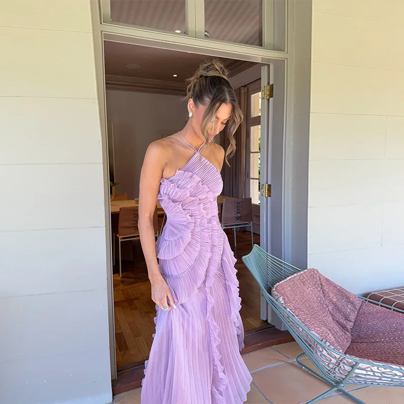 Woman in a purple dress standing in a doorway with a hammock in the background.