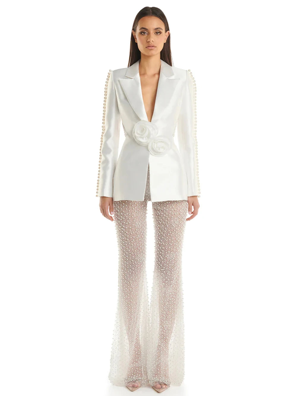 Woman in a stylish white outfit with embellishments standing on a city street.