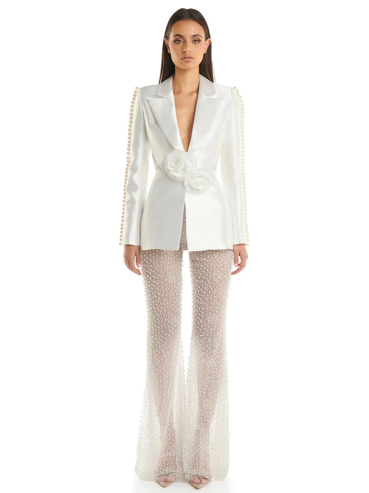 Woman in a stylish white outfit with embellishments standing on a city street.