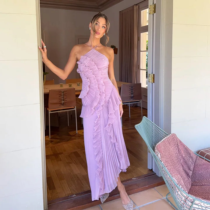 Woman in a pink one-shoulder dress standing in a doorway.