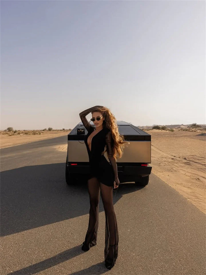 Woman in a black outfit standing next to a futuristic vehicle in a desert setting