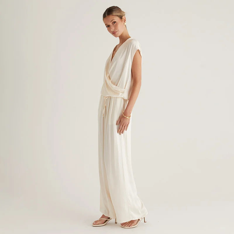 Woman wearing a flowing white dress against a plain background