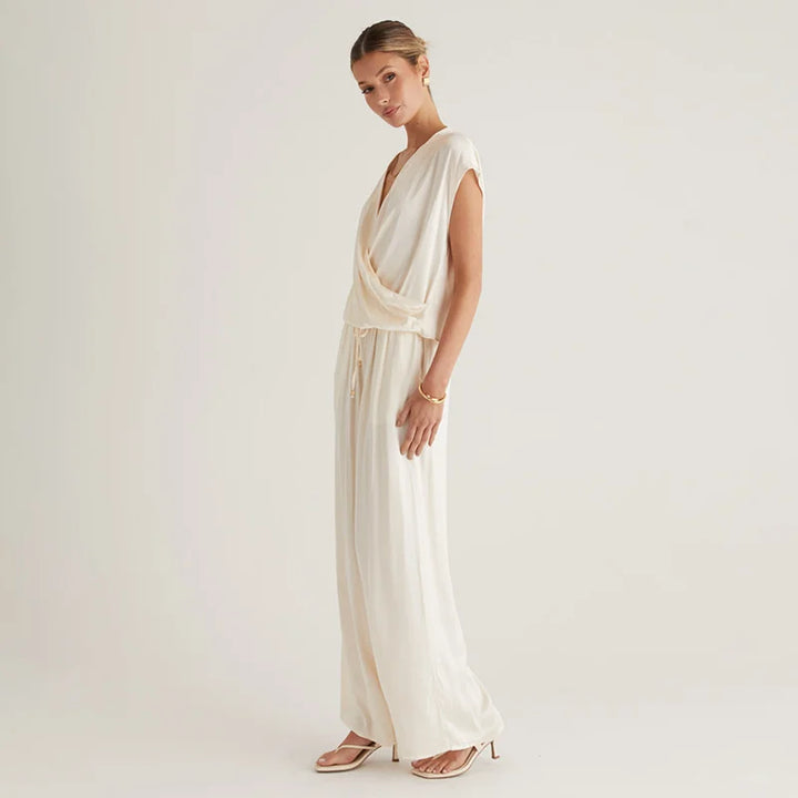 Woman wearing a flowing white dress against a plain background