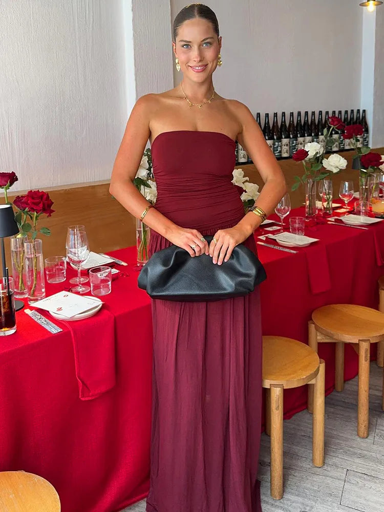 Woman in a burgundy dress holding a black clutch in a restaurant setting.