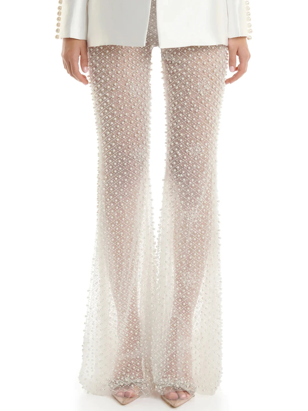 Woman in a stylish white outfit with embellishments standing on a city street.