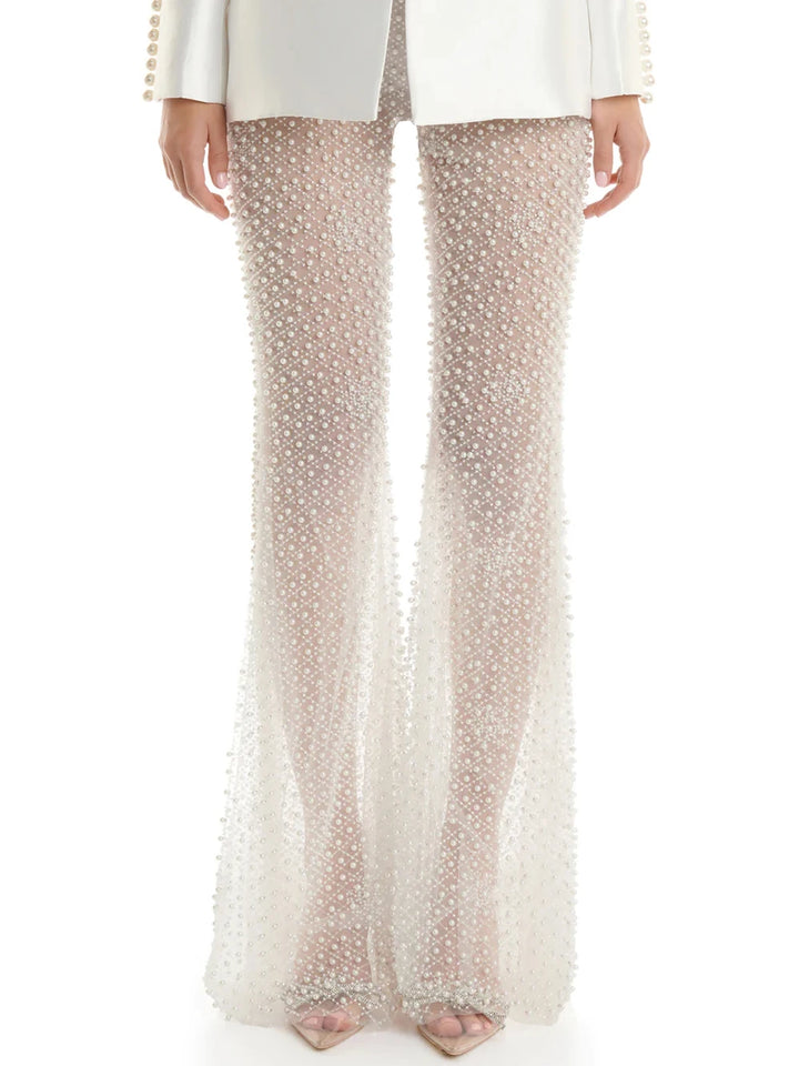 Woman in a stylish white outfit with embellishments standing on a city street.