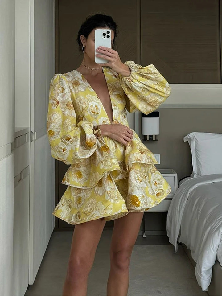 Person wearing a yellow floral dress taking a mirror selfie in a bedroom.