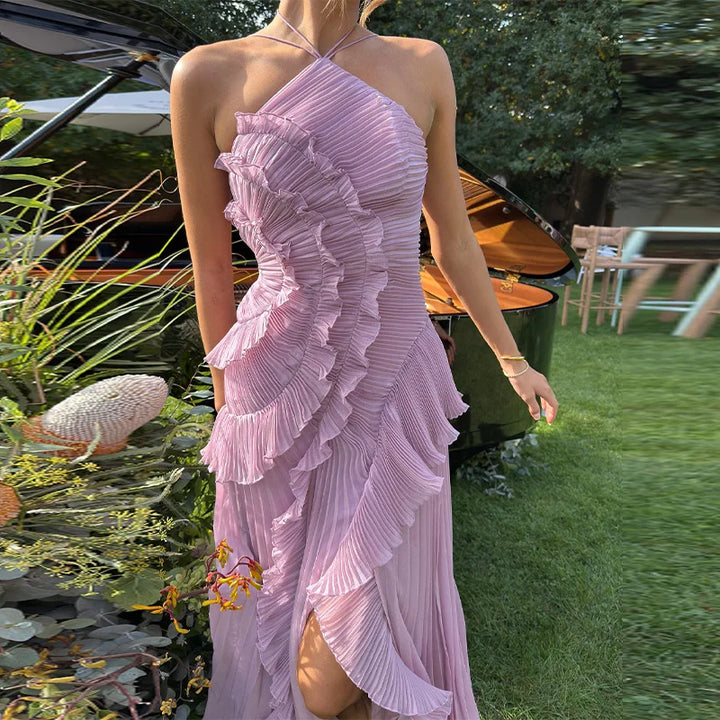Woman in a pink dress standing outdoors with greenery and a piano in the background