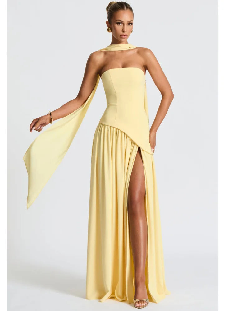 Woman wearing a yellow strapless gown with a slit on a white background