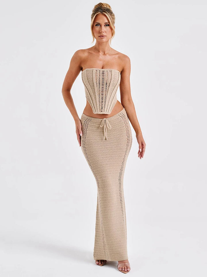 A woman wearing a white two piece set with a strapless bandage crop top and a matching knit skirt.