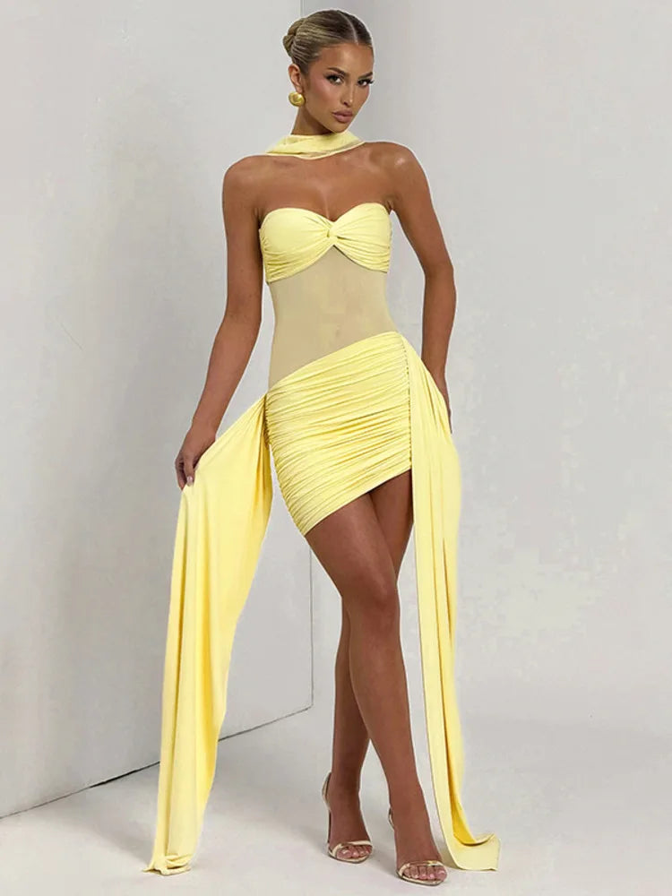 Woman wearing a yellow dress with a sheer overlay on a plain background