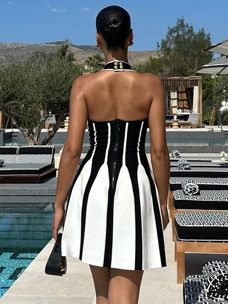 Woman in a black and white dress standing by a poolside.
