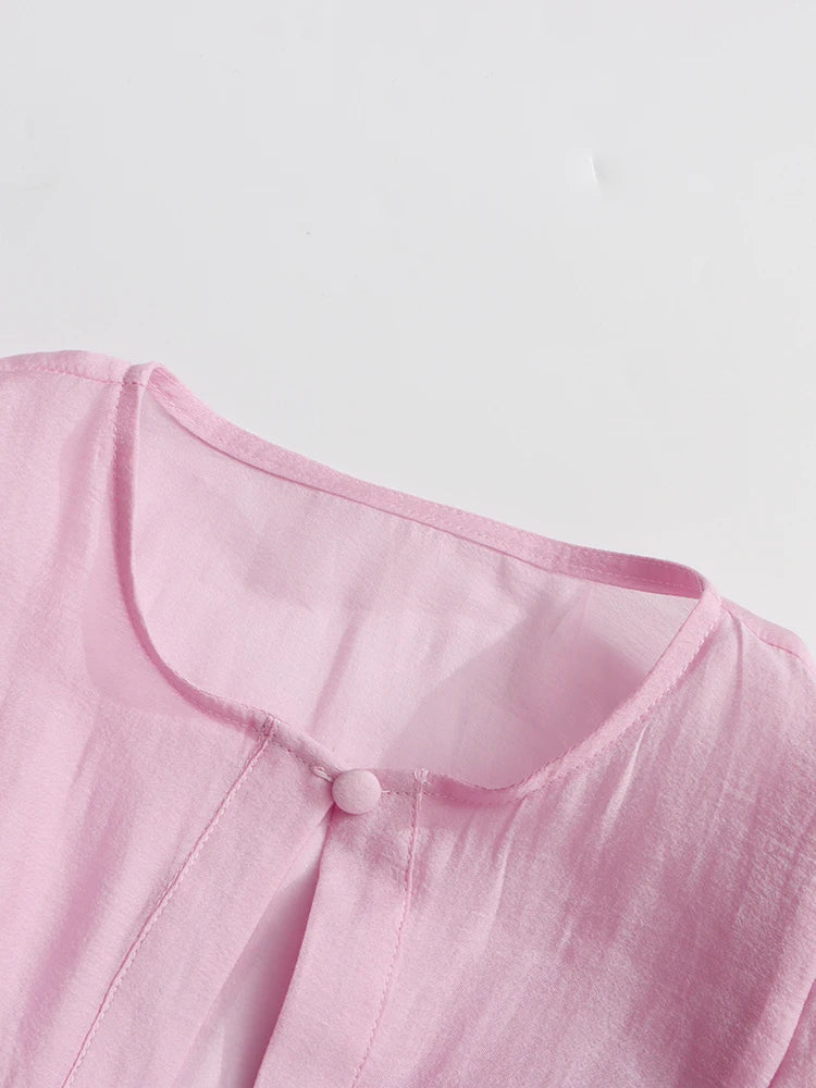 Close-up of a pink garment with a button on a light gray background