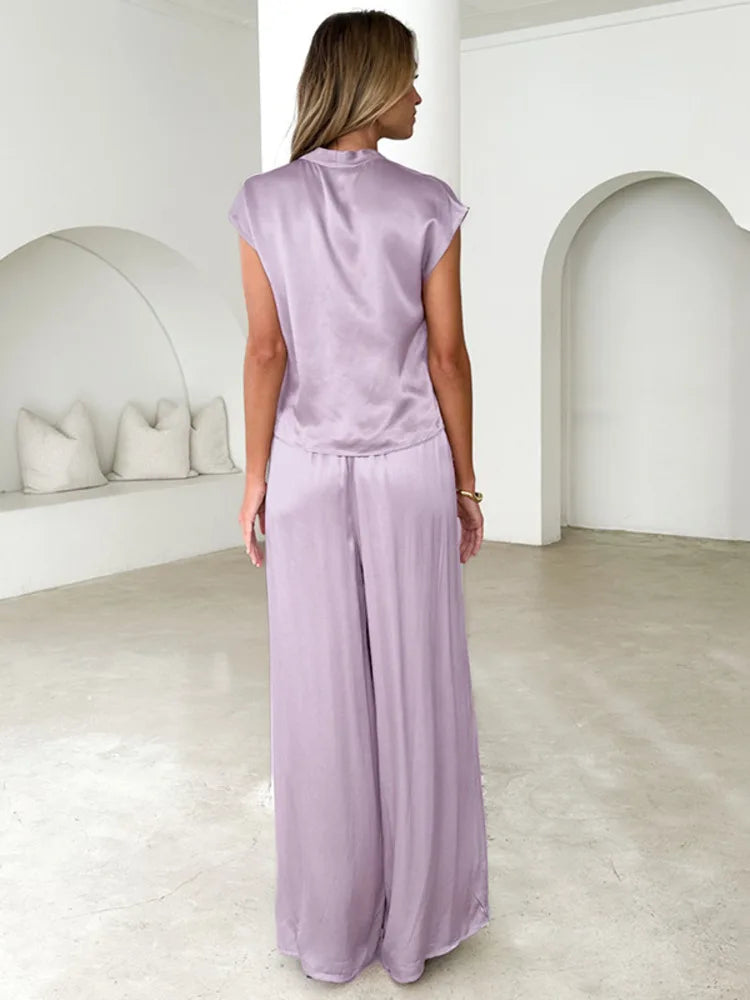 Woman wearing a light purple jumpsuit in a minimalistic room.