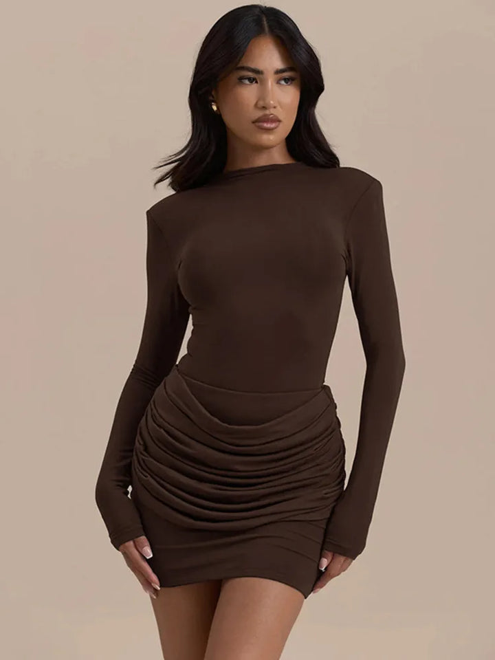 Woman wearing a brown long-sleeve dress against a beige background
