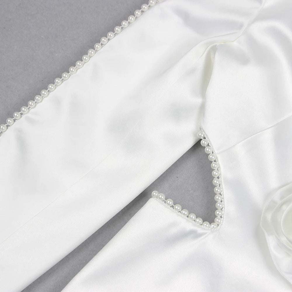 Woman in a stylish white outfit with embellishments standing on a city street.