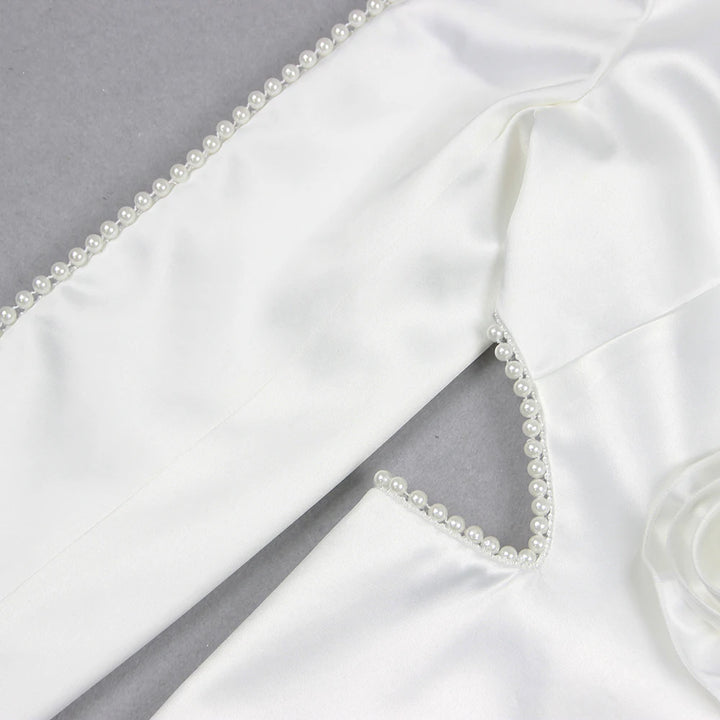 Woman in a stylish white outfit with embellishments standing on a city street.