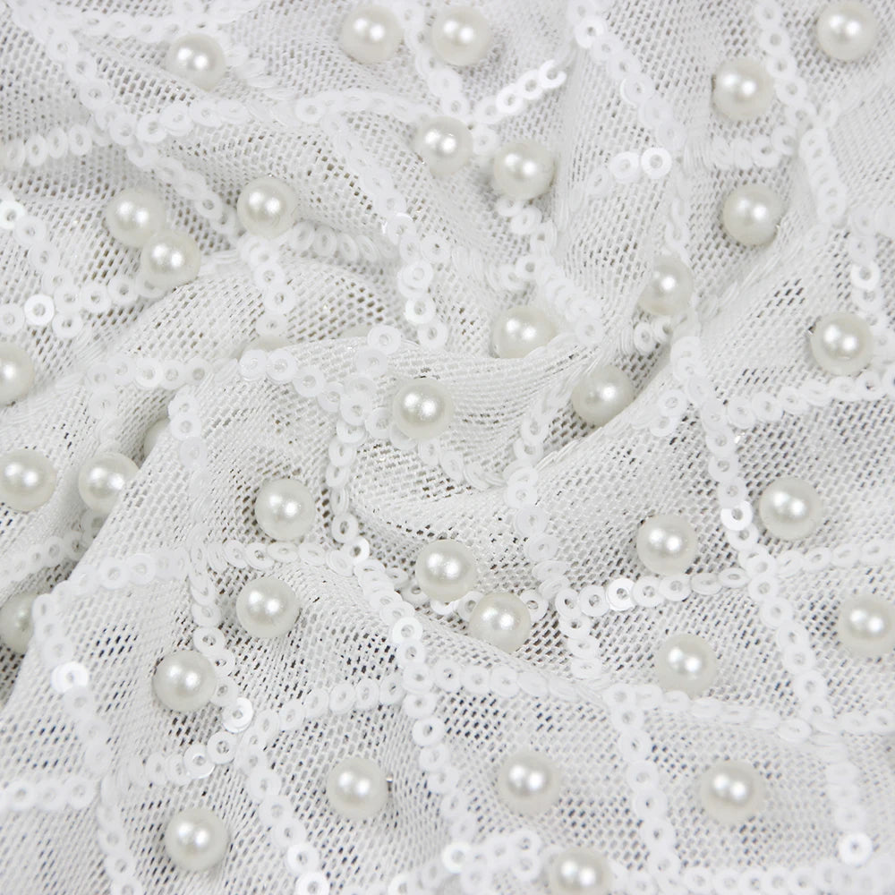 Woman in a stylish white outfit with embellishments standing on a city street.