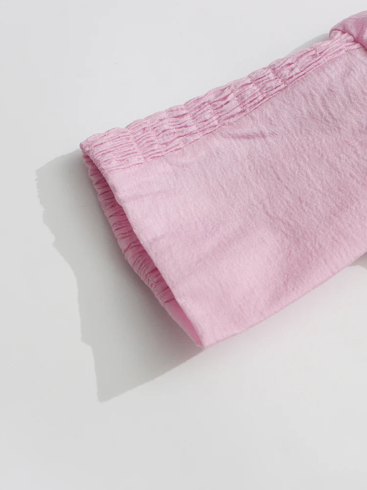 Pink fabric with a textured pattern on a light gray background