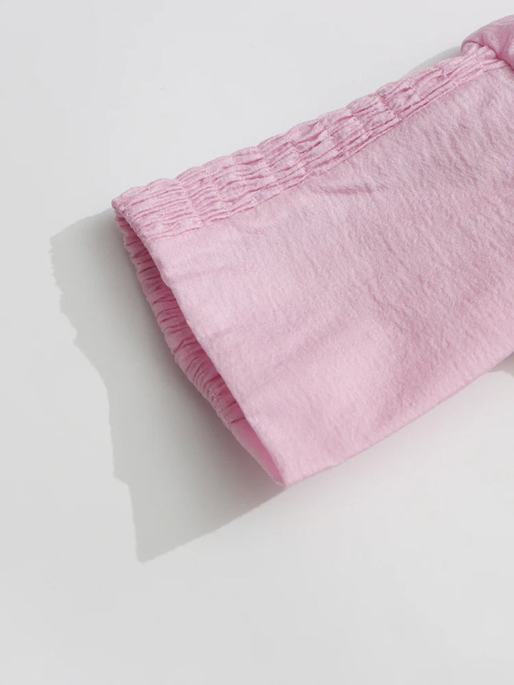 Pink fabric with a textured pattern on a light gray background