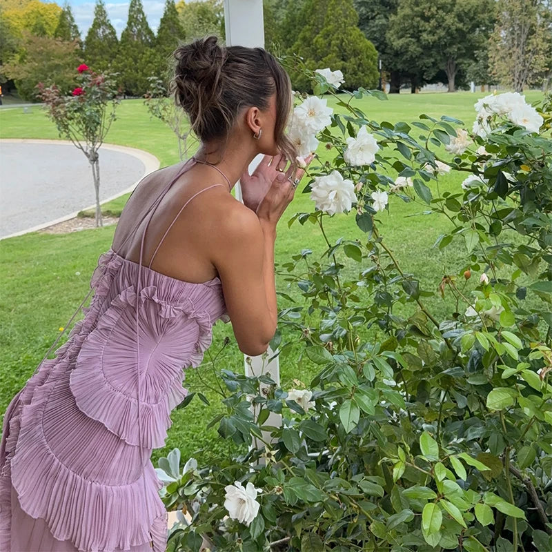 Woman in a purple dress smelling flowers in a garden