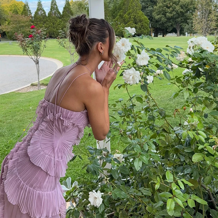 Woman in a purple dress smelling flowers in a garden