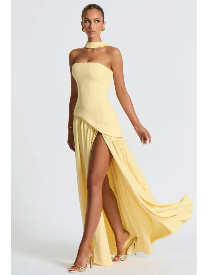 Woman wearing a yellow strapless gown with a slit on a white background