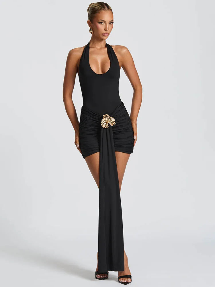 Woman wearing a black halter dress with a gold belt on a white background