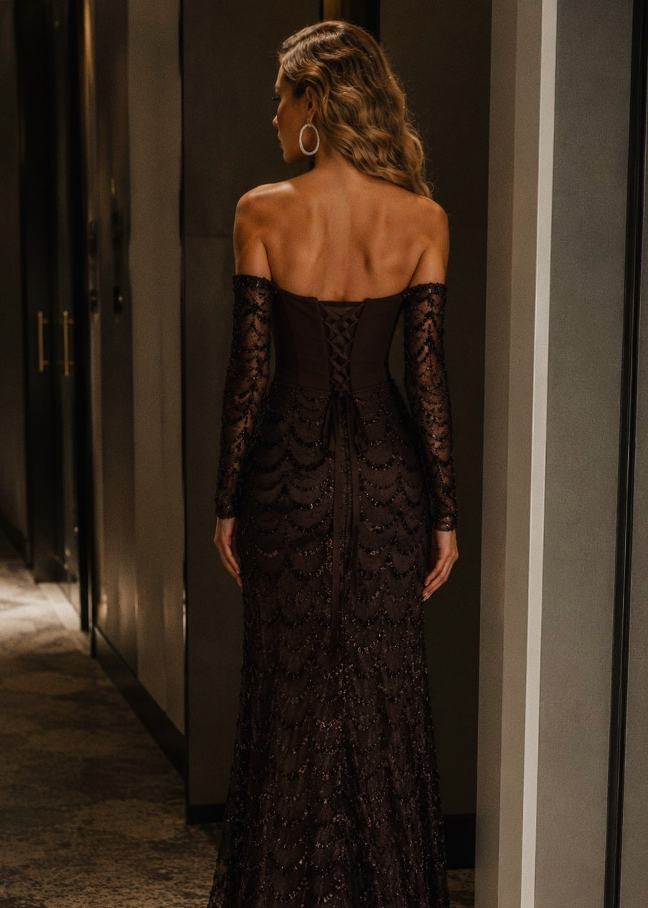 Woman wearing a black lace dress in a dimly lit room.