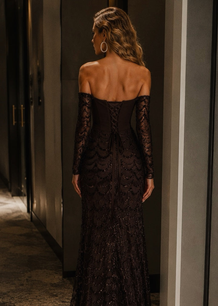 Woman wearing a black lace dress in a dimly lit room.