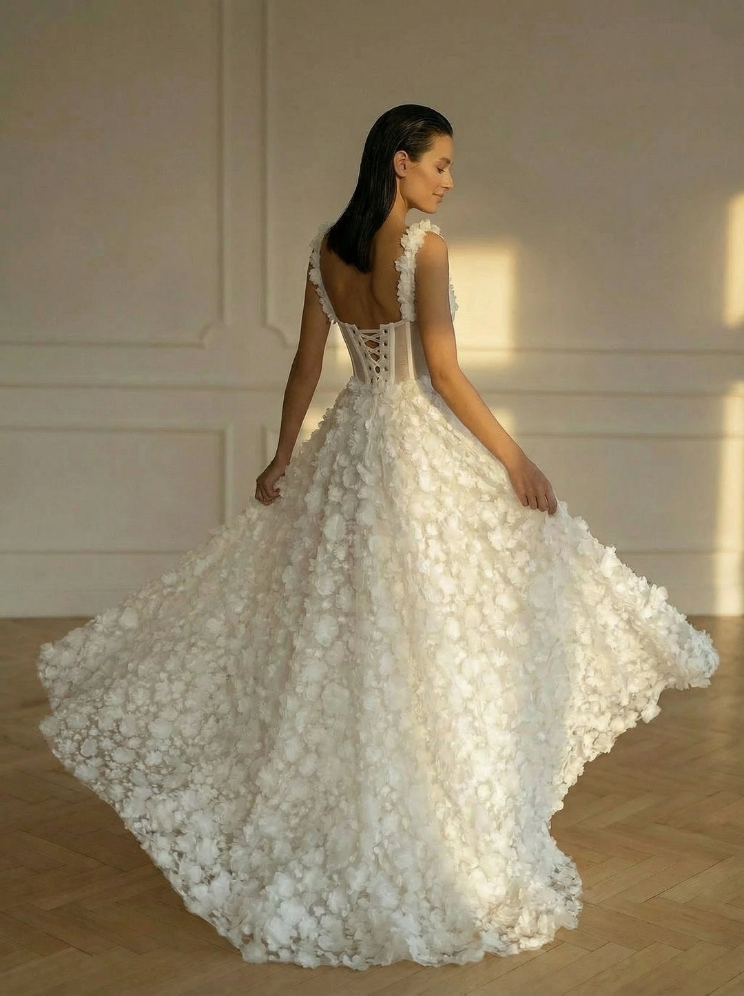 Woman in a white wedding dress with floral details in a softly lit room.