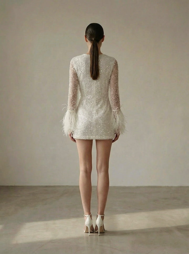 Woman wearing a white lace dress with sheer sleeves against a plain background