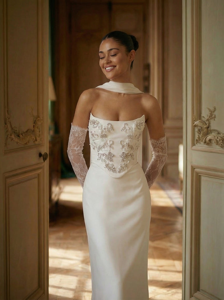 Woman in a white wedding dress with lace detailing standing in a doorway.