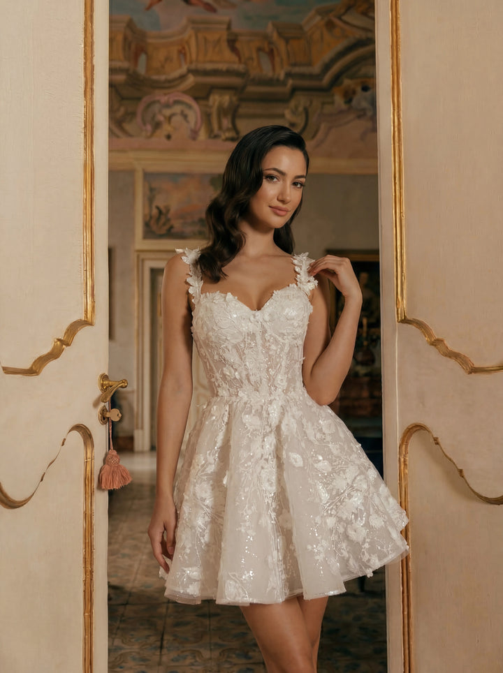 Woman in a white lace dress standing in an ornate room.